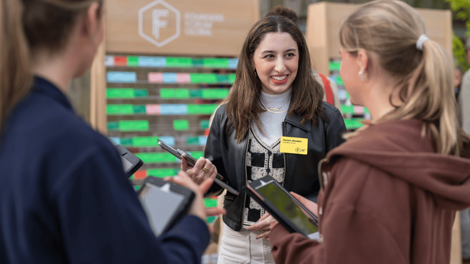 Smiling event organizer with clipboard chatting to two event attendees
